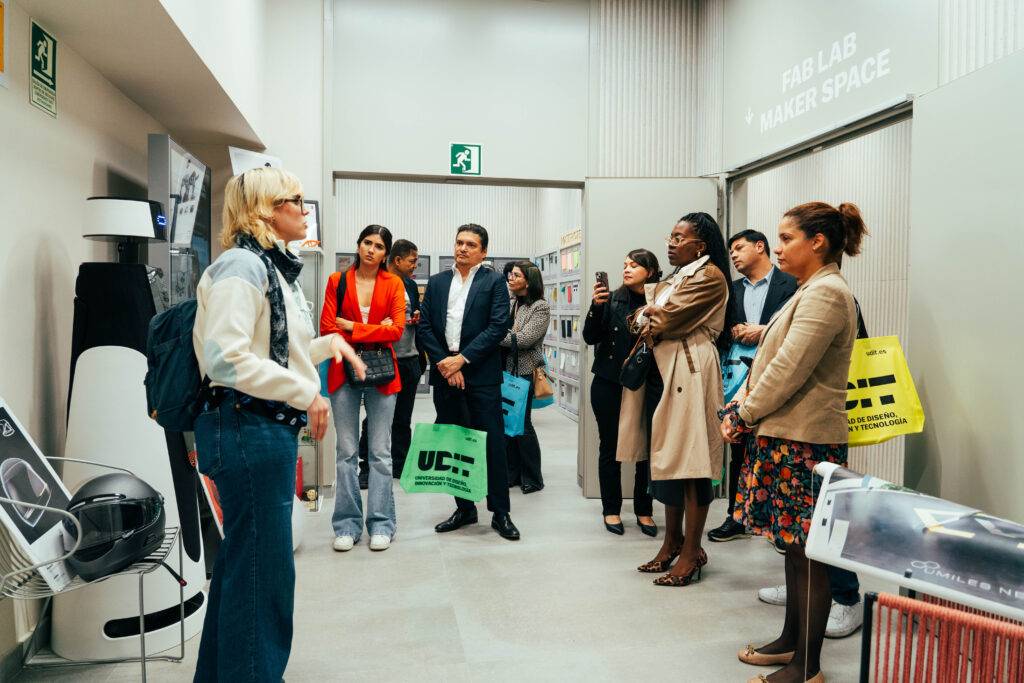 Un grupo de personas escucha atentamente a una presentadora en un espacio moderno de diseño y tecnología.