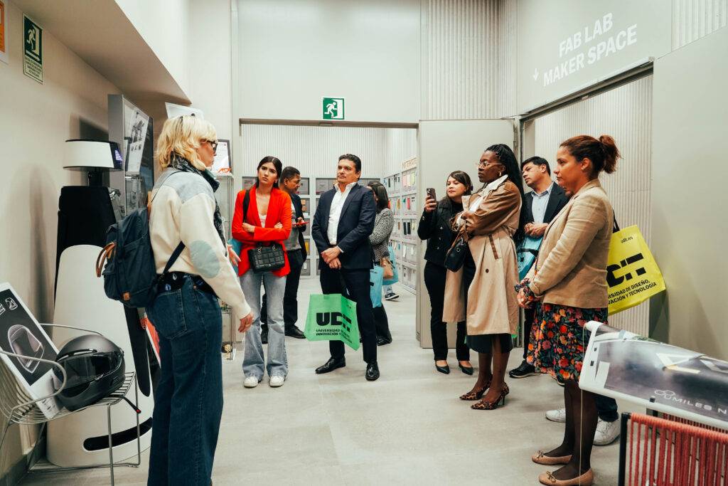 Un grupo de personas escucha atentamente a una expositora en un espacio de fabricación creativa.