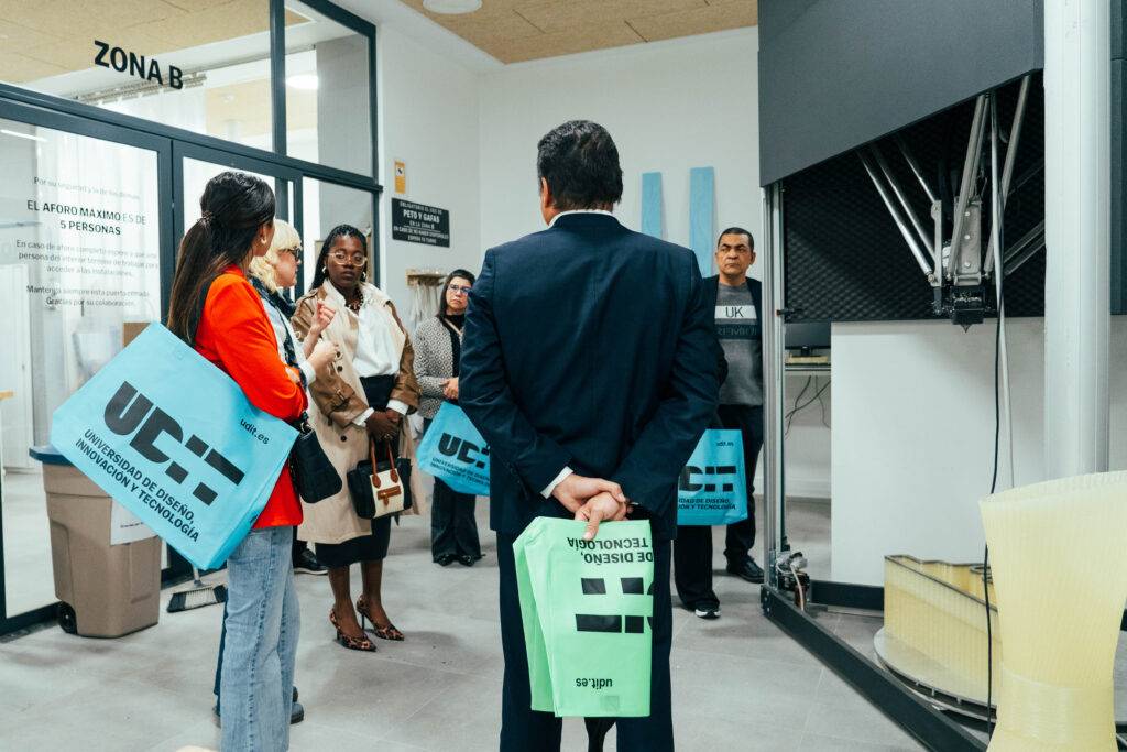 Un grupo de personas se encuentra en un espacio de trabajo, discutiendo mientras sostienen bolsas de tela.