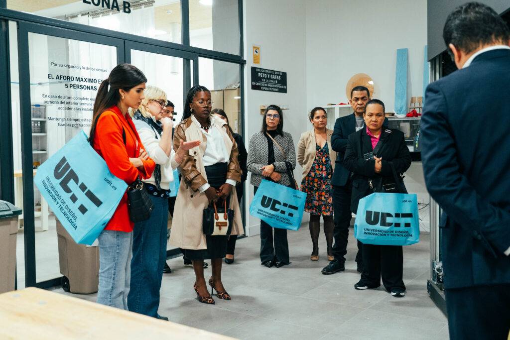 Un grupo de personas con bolsas azules escucha atentamente en un lugar cerrado.