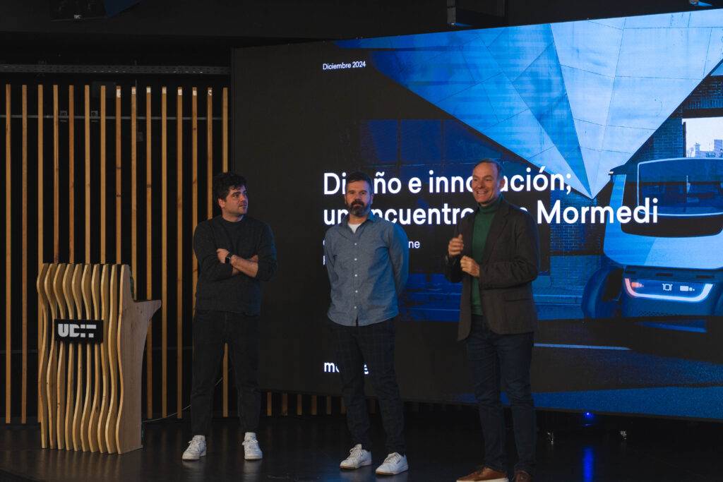 Tres personas en un escenario discutiendo sobre diseño e innovación.