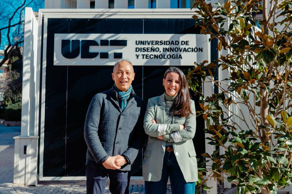 Dos personas posando frente al edificio de la Universidad de Diseño, Innovación y Tecnología.