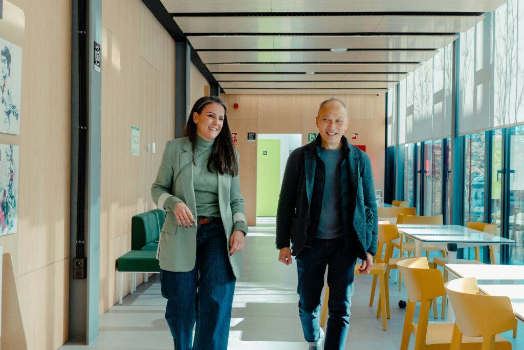 Dos personas caminan por un pasillo iluminado con paredes de madera y muebles modernos.