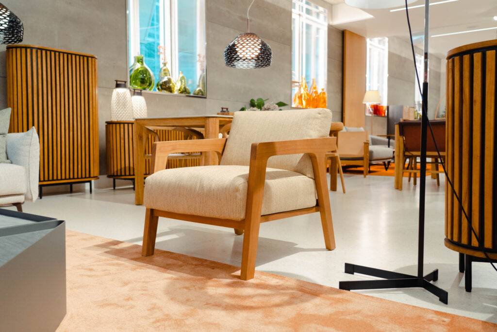 Sala de exhibición con muebles modernos y un sillón de madera clara.