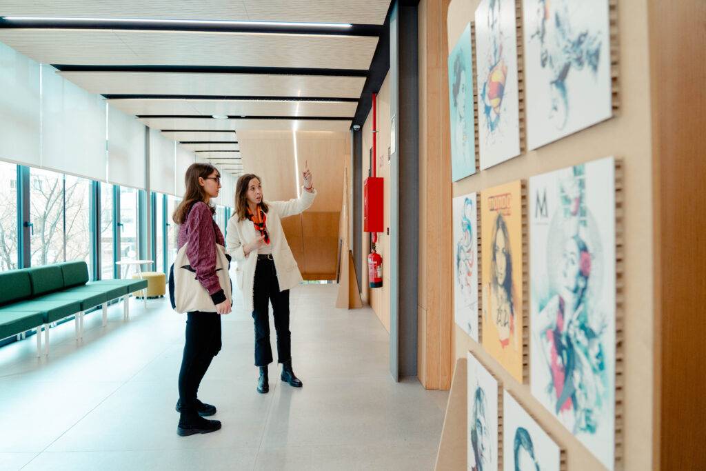 Dos personas observan y comentan obras de arte en una galería.