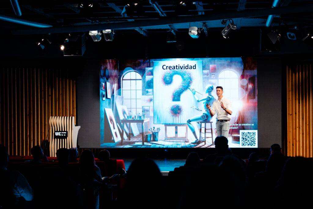 Una persona presenta en un escenario con una pantalla que muestra un gráfico relacionado con la creatividad.