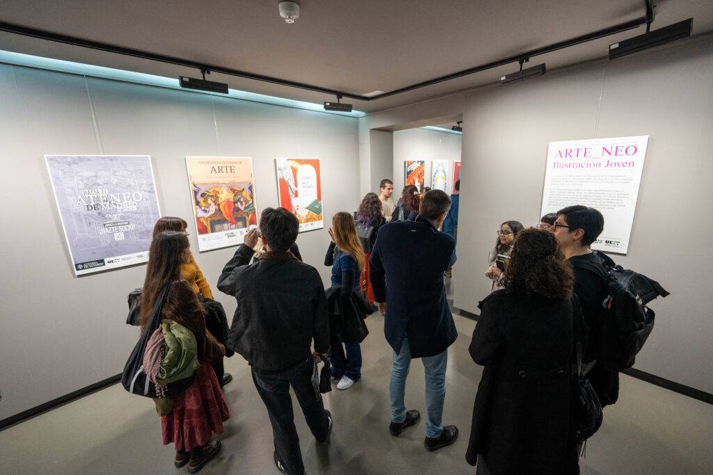 Un grupo de personas observa diversas obras de arte en una galería.