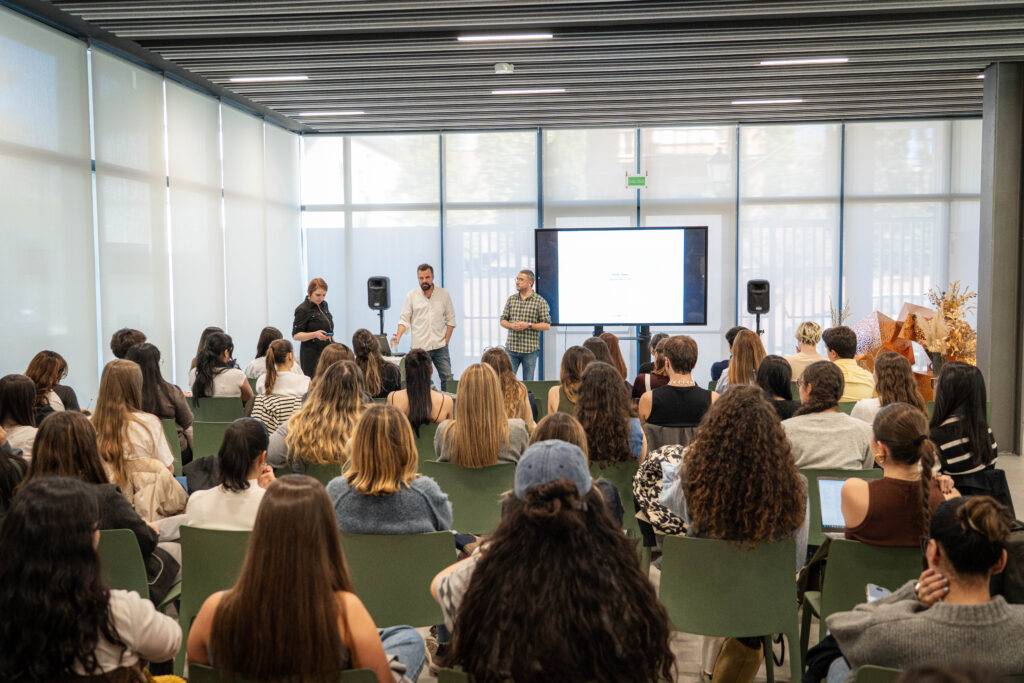 Un grupo de personas asiste a una presentación en un espacio moderno y luminoso.