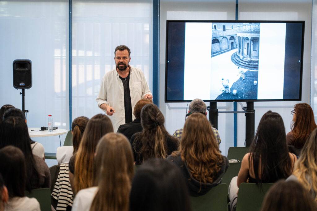 Una persona está presentando frente a una audiencia mientras se proyecta una imagen en una pantalla.