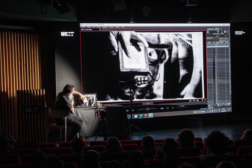 Una persona interactúa con un proyector mientras una imagen se exhibe en una pantalla grande.