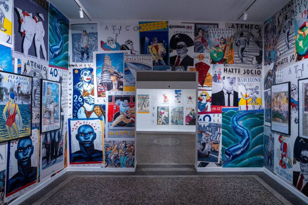 La imagen muestra una sala con paredes decoradas con una variedad de murales y carteles artísticos coloridos.