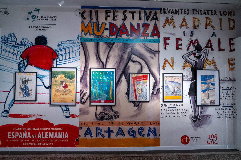 La imagen muestra una exposición con carteles de eventos culturales y deportivos en un mural.