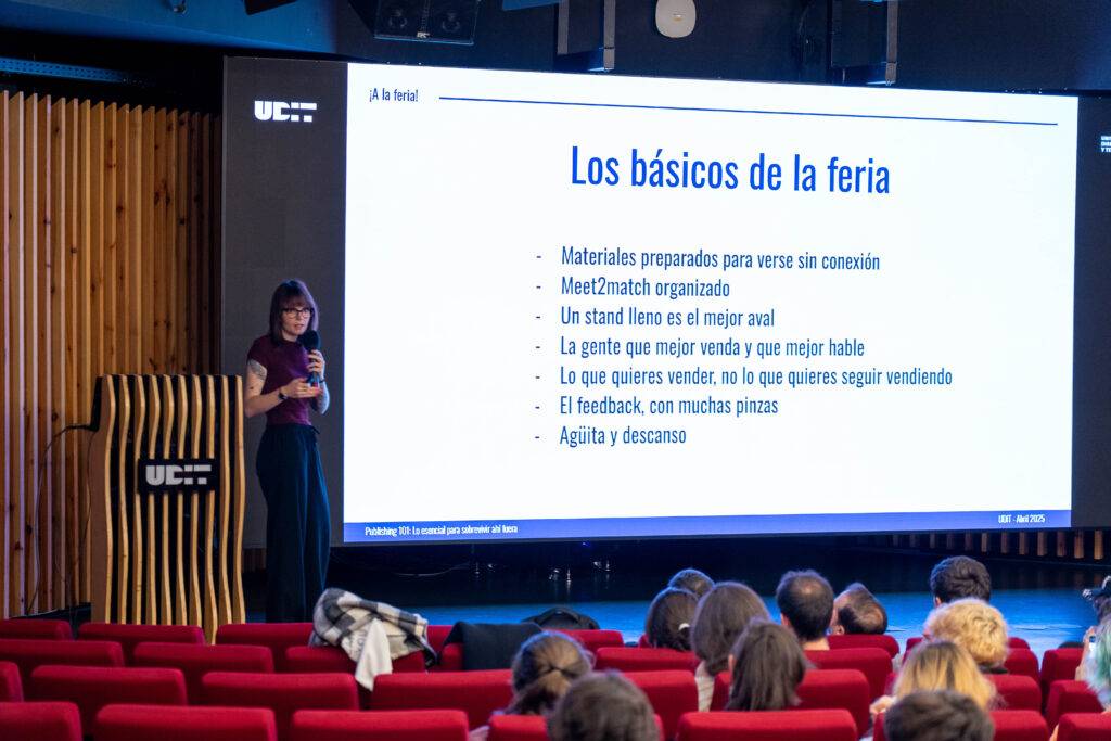 Una presentadora en un evento explica los conceptos básicos de una feria ante una audiencia.