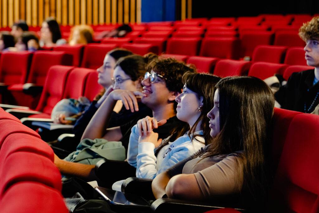 Un grupo de jóvenes atentos durante una proyección en un cine.