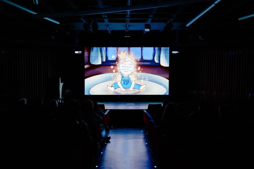 Una proyección animada en una sala oscura con personas observando.