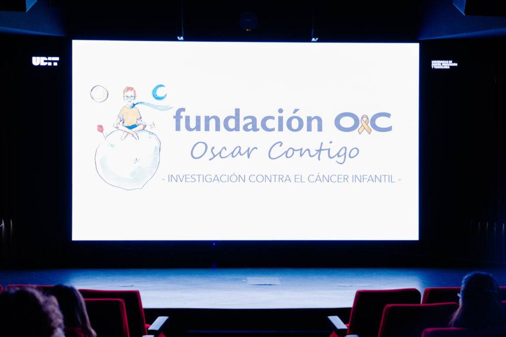 La imagen muestra una pantalla con el logotipo de la Fundación Óscar Contigo, dedicada a la investigación contra el cáncer infantil.