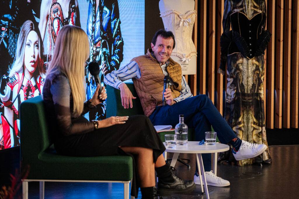 Una presentación en un evento de moda con dos ponentes conversando sobre tendencias.
