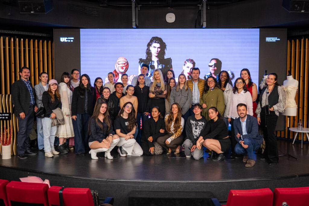 Un grupo de personas posando junto a una pantalla con imágenes en un evento.