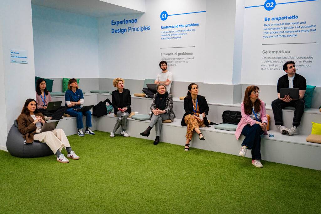 Un grupo de personas sentadas en un espacio moderno, discutiendo sobre principios de diseño de experiencia.