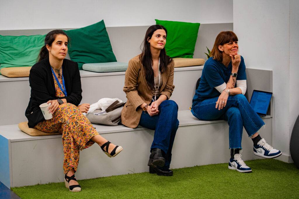 Tres mujeres sentadas en un espacio acogedor, observando con atención.