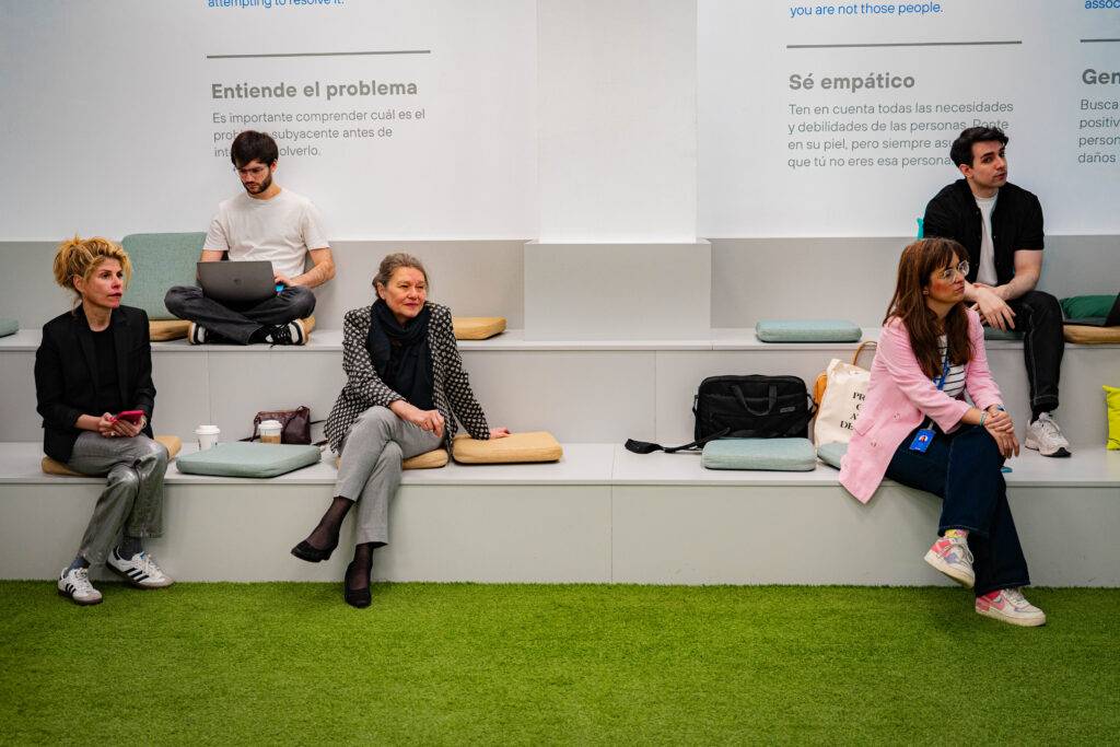 Grupo de personas sentadas en un espacio moderno, interactuando y reflexionando sobre un tema.