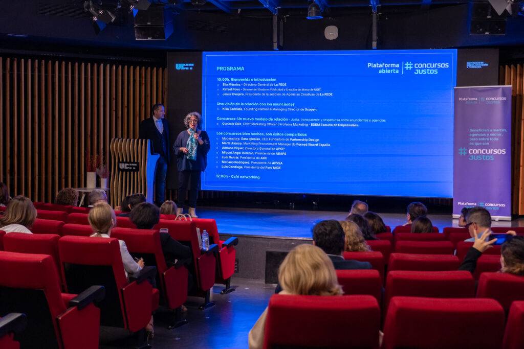 Una presentación en un evento con oradores ante una audiencia en un auditorio moderno.