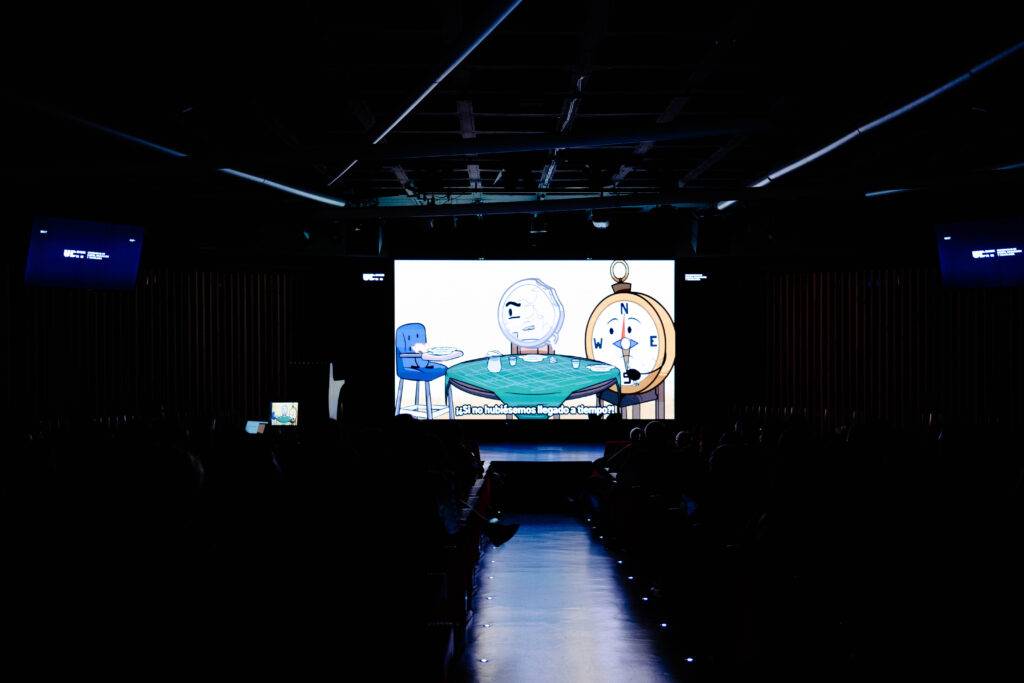 Una presentación en un escenario con una proyección de un video animado en una conferencia.