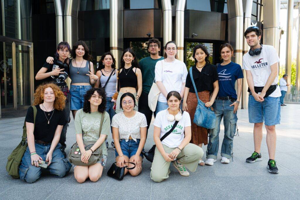 Un grupo de jóvenes posando juntos frente a un edificio moderno.