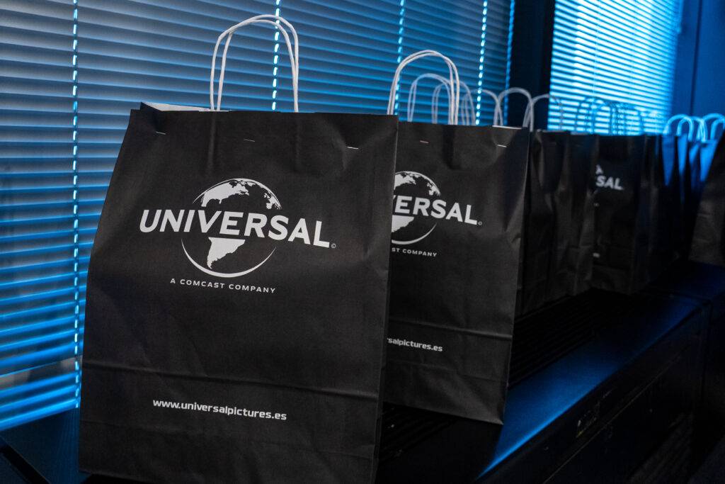Una serie de bolsas negras con el logotipo de Universal en un entorno de oficina.