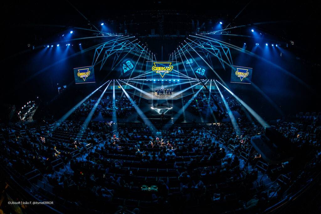 Una imagen de un evento en un gran recinto con luces brillantes y un escenario destacado.