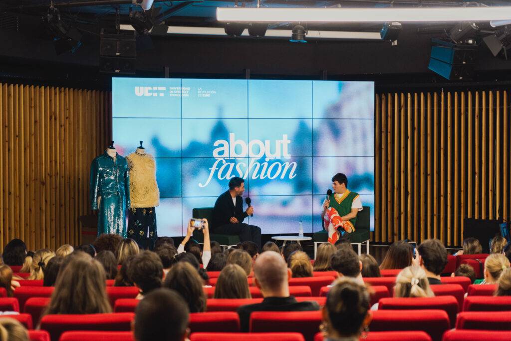 Una conferencia sobre moda con un panel de expositores y una audiencia atenta.