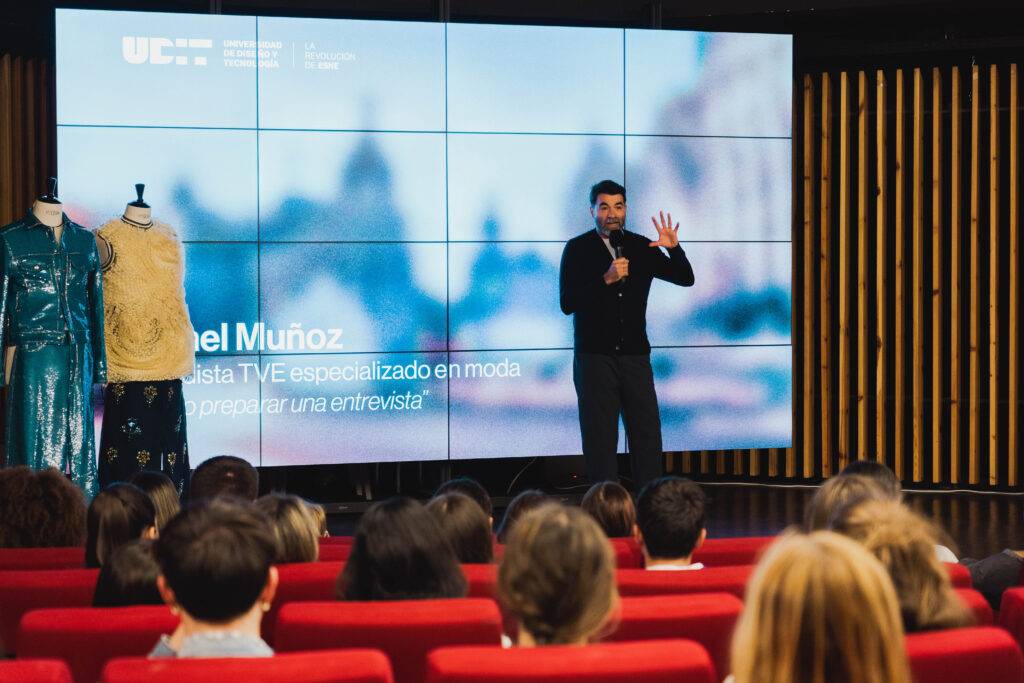 Un presentador desde un escenario habla sobre moda frente a una audiencia.