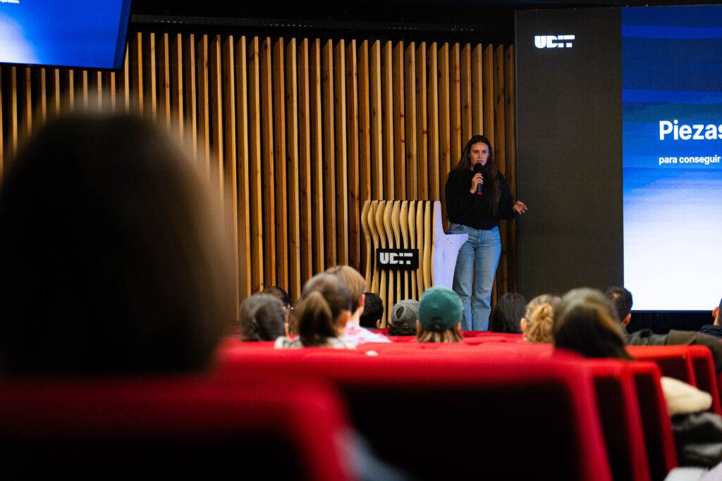 Una persona está haciendo una presentación frente a un público en un auditorio moderno.