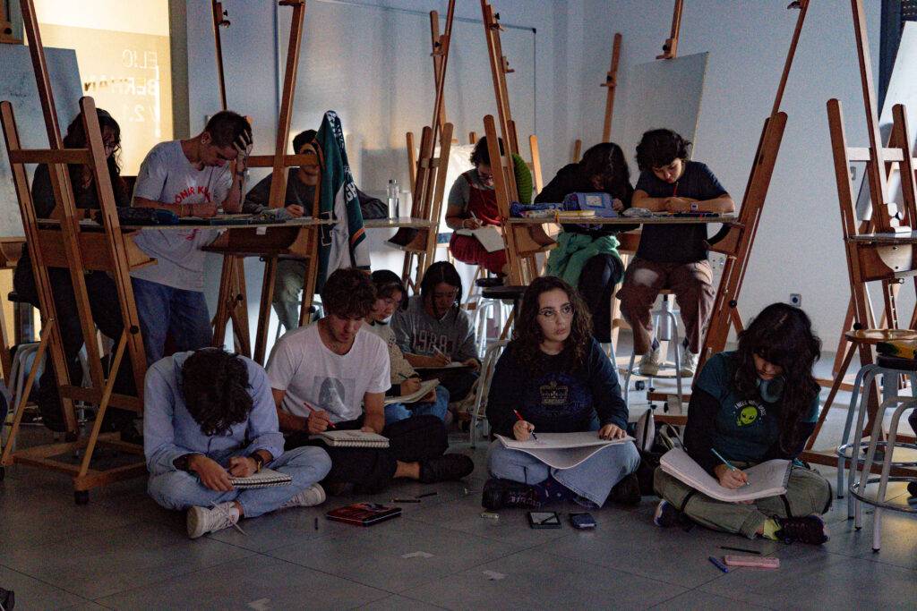 Un grupo de estudiantes de arte se encuentra dibujando en un aula con caballetes.