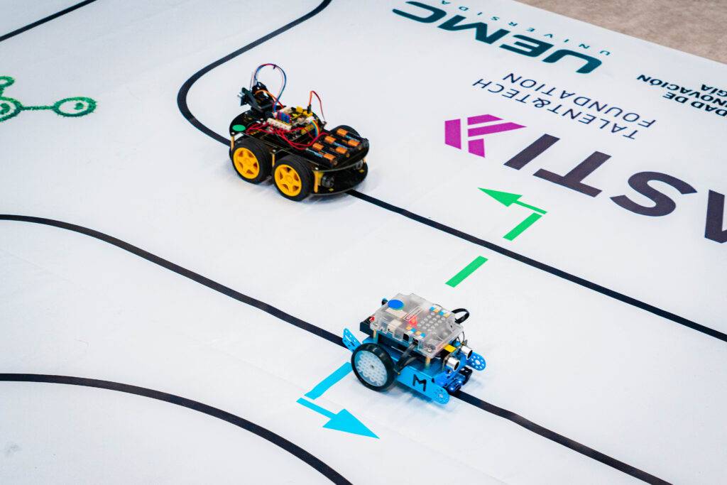 Dos robots se encuentran compitiendo sobre una pista marcada.