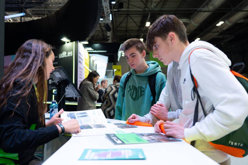 Un grupo de jóvenes interactúa con una representante en un evento educativo.