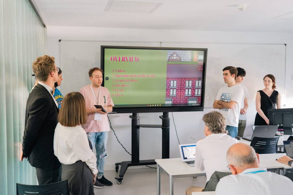 Un grupo de personas presenta un proyecto en un aula frente a una pantalla grande.