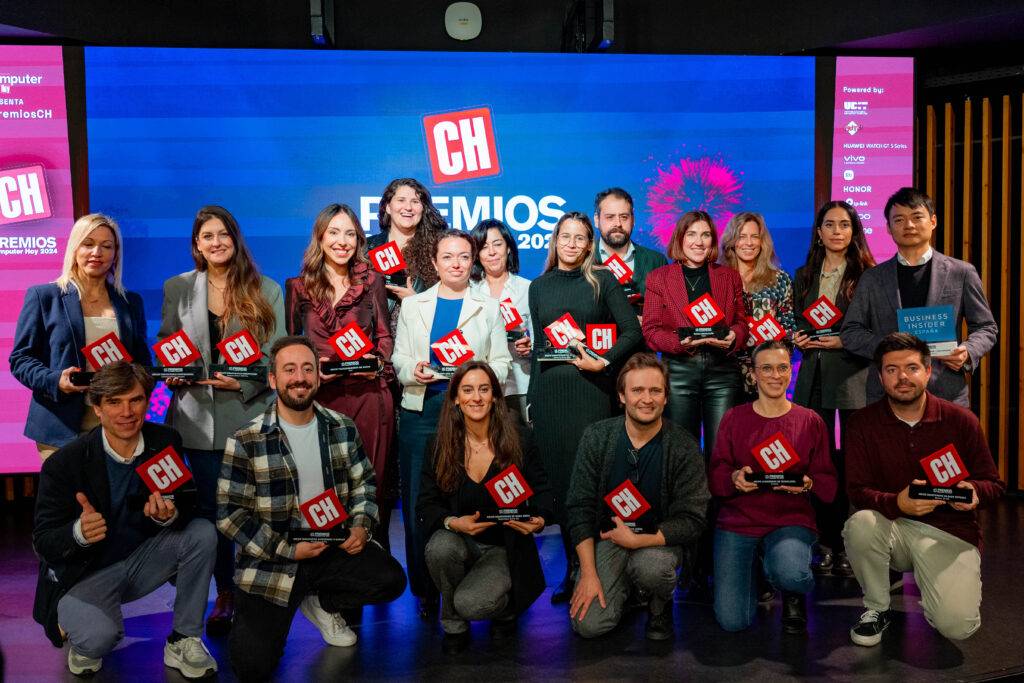 Un grupo de personas posando juntas en un evento de premiación mostrando sus trofeos.