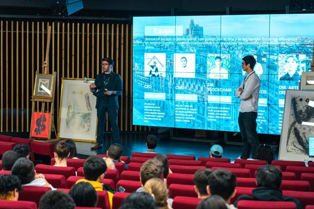 Una presentación en un auditorio con un ponente en el escenario y una audiencia atenta.