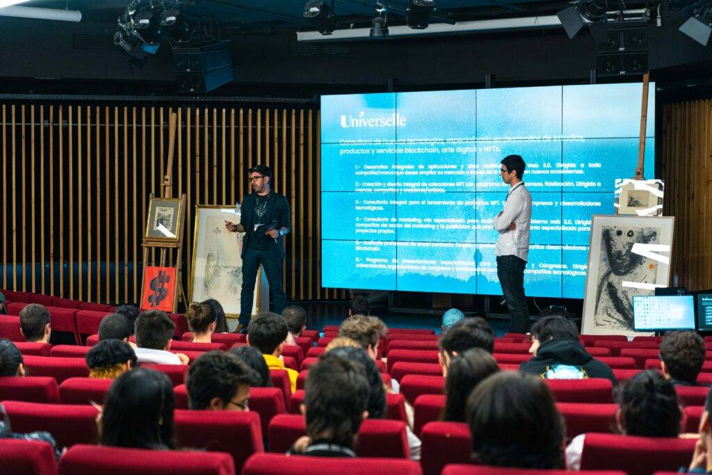 Una presentación en un auditorio con dos oradores y el público atento.