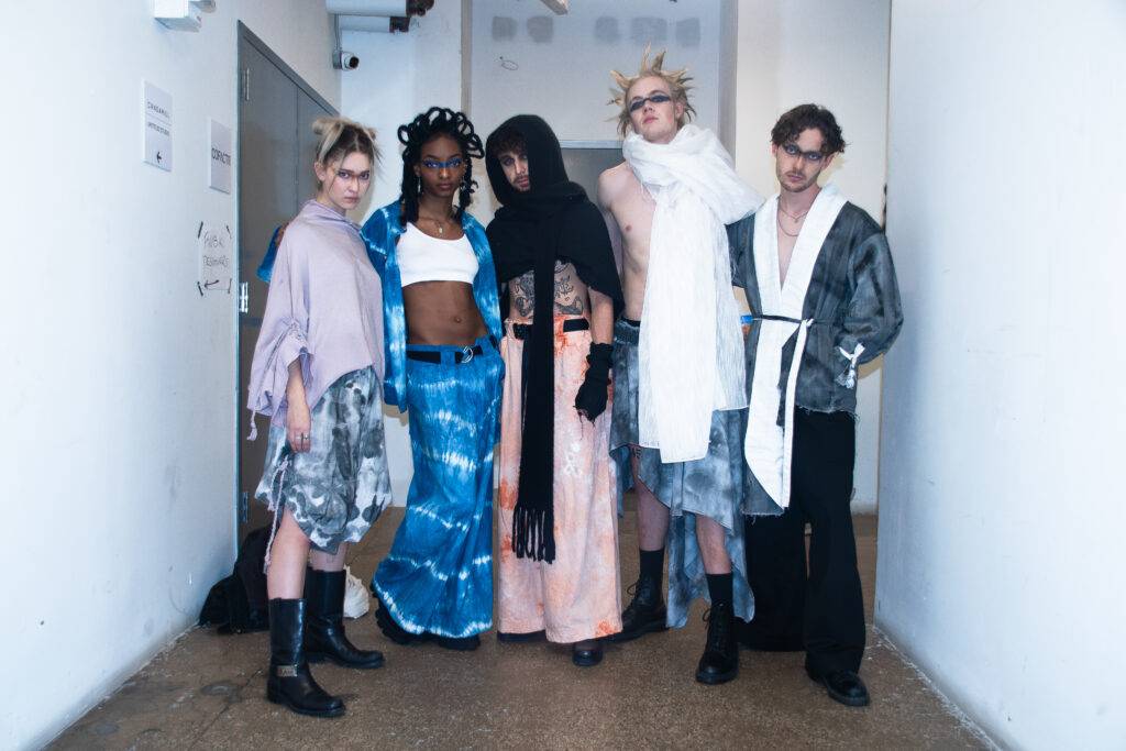 Un grupo de modelos con estilismos variados posan en un pasillo.