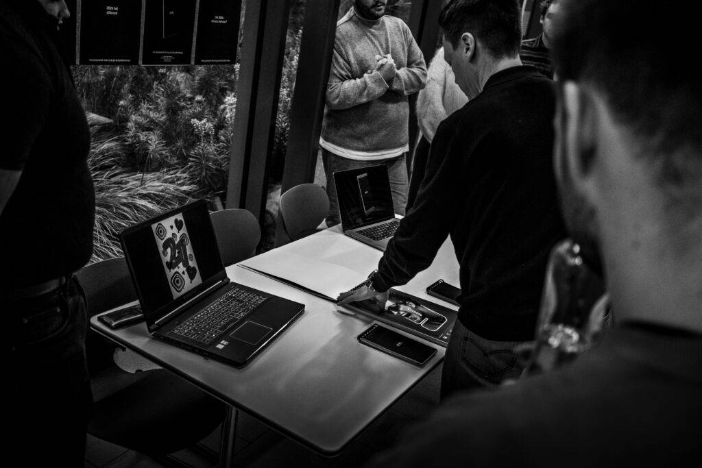 Un grupo de personas observa varios dispositivos electrónicos en una mesa.