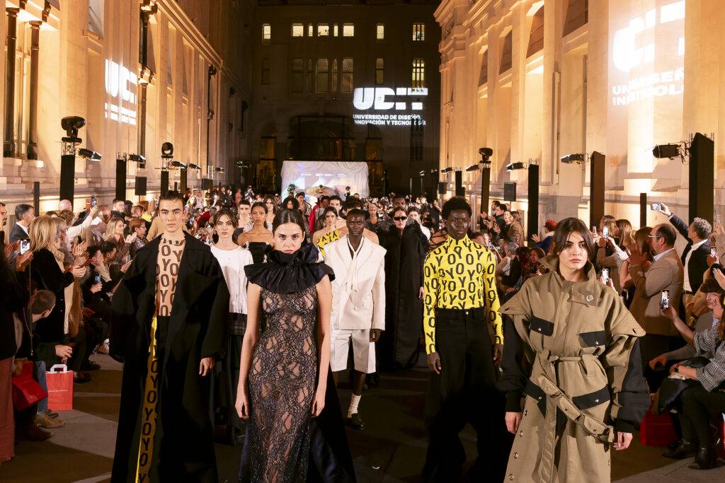 Un desfile de moda con varios modelos caminando por una pasarela en un evento al aire libre.