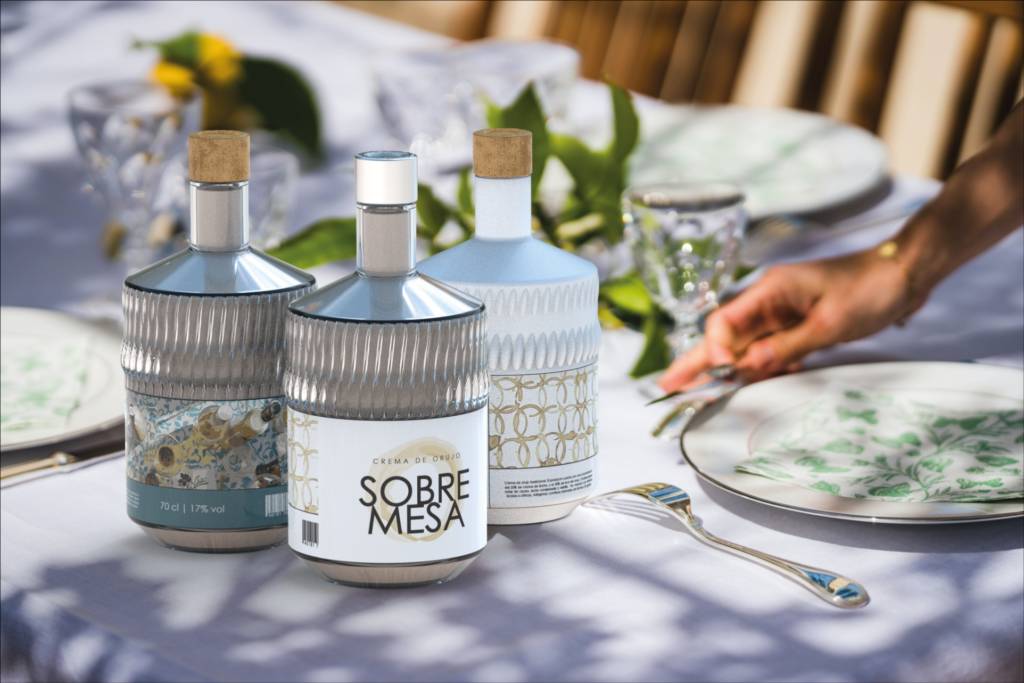 La imagen muestra tres botellas decorativas sobre una mesa con un ambiente elegante y natural.