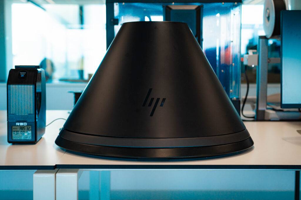 Un dispositivo electrónico negro con forma cónica se encuentra sobre una mesa en un entorno moderno.