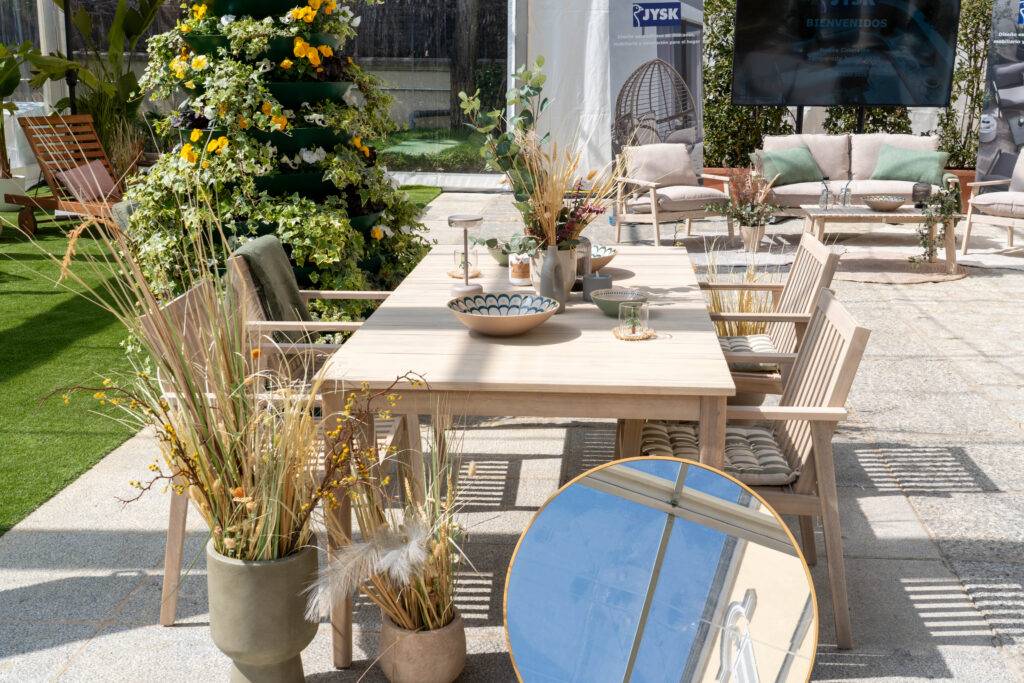 Un elegante conjunto de mesa y sillas de jardín decorado con plantas y un espejo.