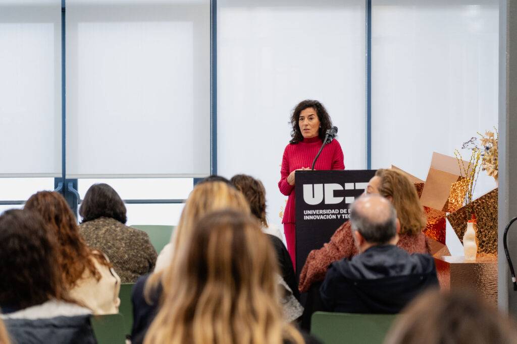 Una mujer habla frente a un público durante un evento en la universidad.