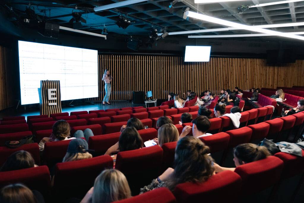 Una mujer presenta ante un grupo de personas en una sala de conferencias.