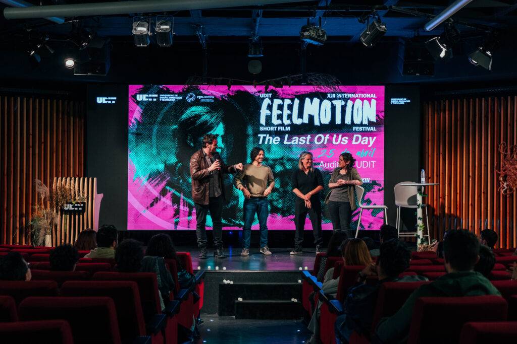 Un evento de proyección de cortometrajes en un auditorio con un fondo colorido.