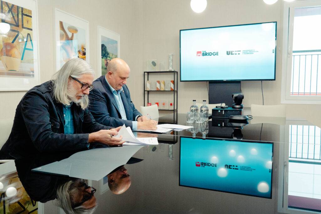Dos hombres están sentados en una mesa revisando documentos en una sala de reuniones.